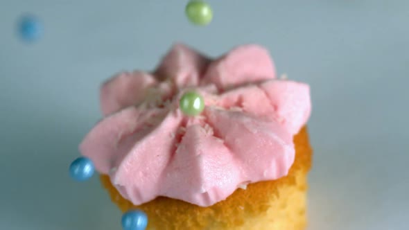 Sugar Balls Falling Onto Cupcake With Pink Frosting