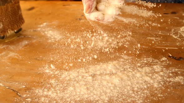 Hand Sprinkling Flour Over Wooden Table