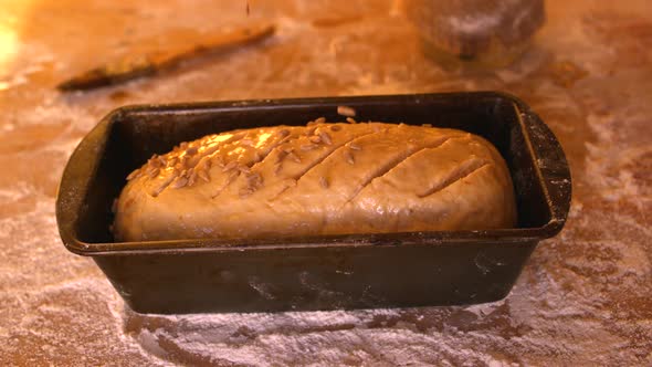 Seeds Being Sprinkled Over Dough In Loaf Tin On A Floury Table