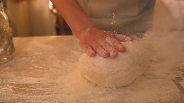 Hands Dropping Ball Of Dough Onto Floury Surface
