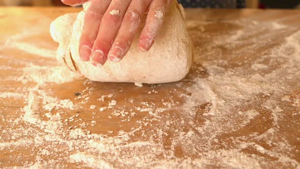 Hands Kneading Ball Of Dough On A Floury Surface