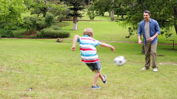 Father And Son Kicking A Football Back And Forth