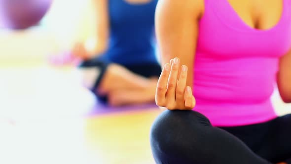 Mid Section On Meditating Young Women Sitting On Exercise Mats