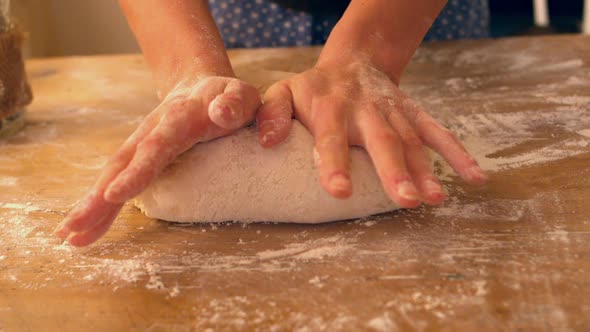Female Hands Kneading Ball Of Dough On A Floury Surface