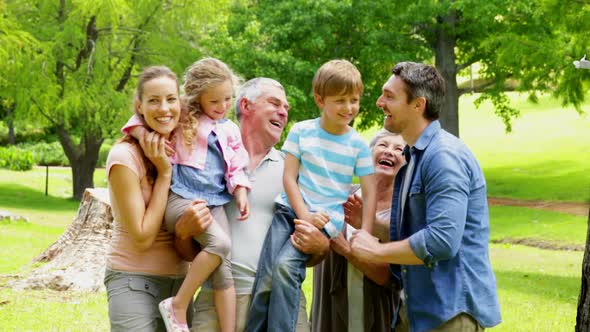 Multi Generation Family Posing And Laughing At Camera In A Park