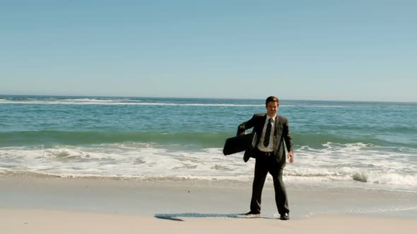 Happy Businessman Throwing His Suitcase On The Beach alt