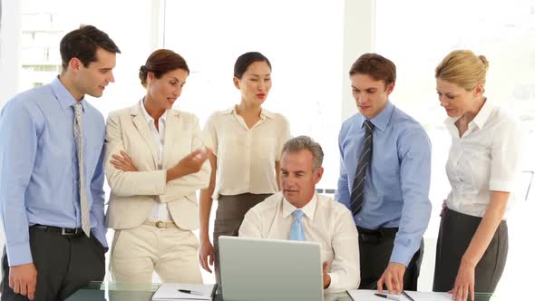 Business Team Talking In Front Of Laptop Then Pointing To Camera