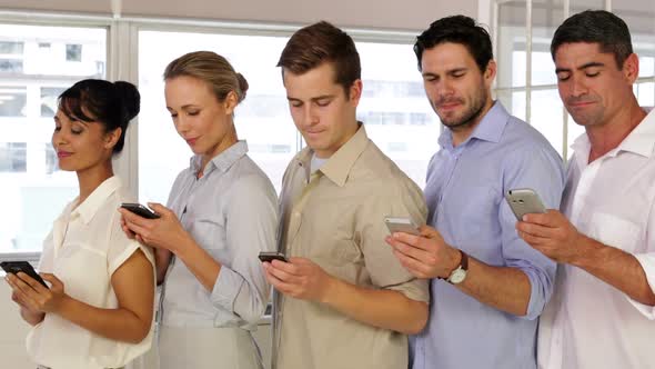 Content Businesspeople Text Messaging While Standing In A Row