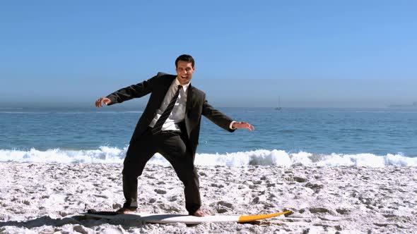 Businessman Balancing On Surfboard On The Beach