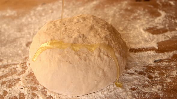 Olive Oil Being Poured Over Dough On A Floury Table