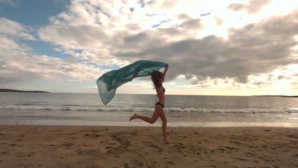 Woman Running At The Beach Holding A Scarf