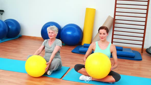 Trainer And Elderly Client Raising Exercise Balls alt