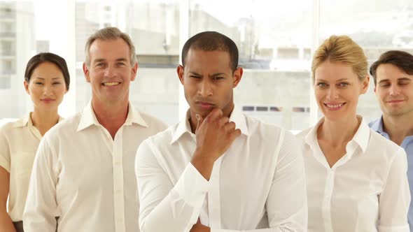 Businessman Looking At Camera With Staff Behind Him alt