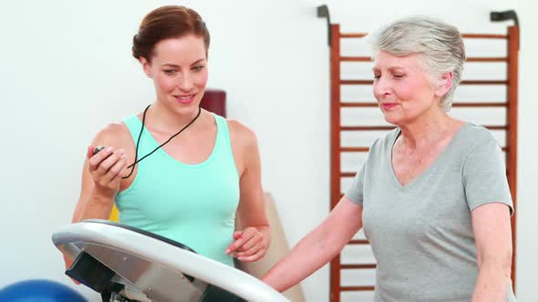 Trainer Watching Elderly Client Using Treadmill