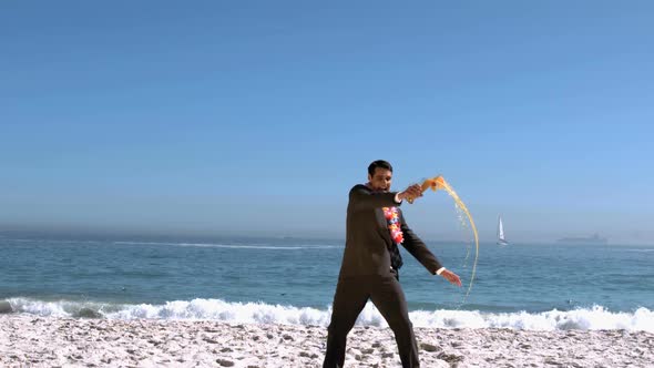 Businessman On The Beach Throwing His Cocktail Glass alt
