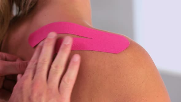 Physiotherapist Applying Pink Kinesio Tape To Patients Back