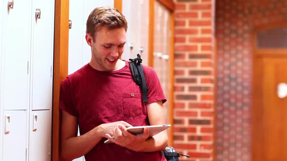 Happy Student Using Tablet Leaning Against Locker