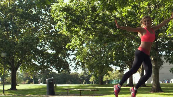 Happy Toned Blonde Jumping In The Air In Park alt