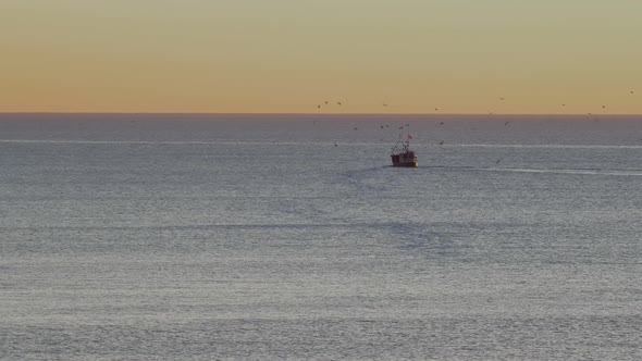 Fisherman's ship goes in to the calm sea in the sunset