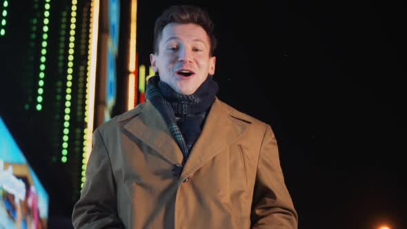 Happy Smiling Successful Man Walks on Winter Night Along Street Glowing City