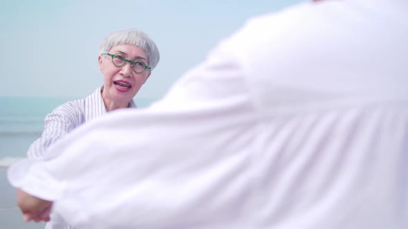 A senior woman dancing with her partner on the beach.