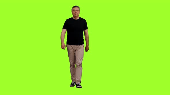 Adult Man in Black T-shirt Walks on Green Background