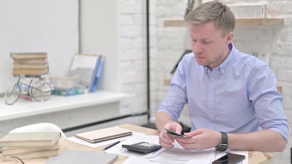 Unhappy Businessman Counting Money and Calculating