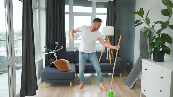 Man Cleaning the House and Having Fun Dancing with a Broom