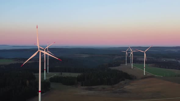 Wind Turbines Array in a Countryside Landscape, Aerial View. Spinning Blades and Towers in Twilight,