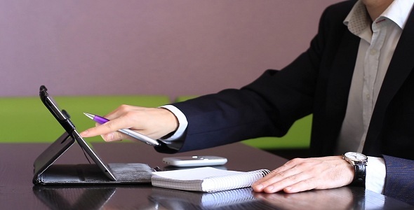 Man Working On The Tablet And Writes In A Notebook