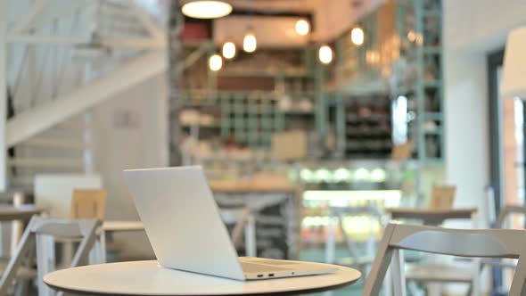 Young African Man Coming Back and Working on Laptop in Cafe