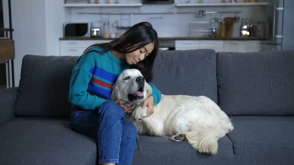 Smiling Woman Sitting with Lying Dog on Sofa