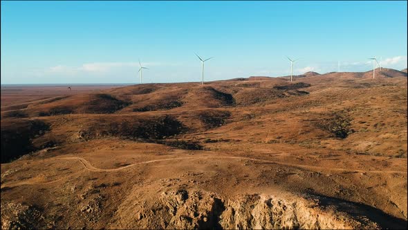 Wind farm towers rise majestically above the barren desert landscape