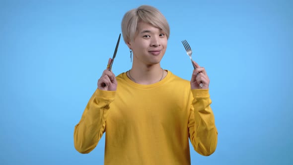 Portrait of Hungry Asian Man with Fork and Knife