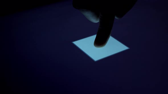 Human finger is pressing a digital button on a glowing touchscreen.