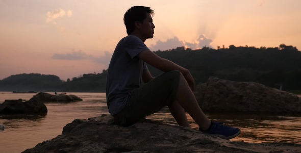 Asian Man Sitting At River Side