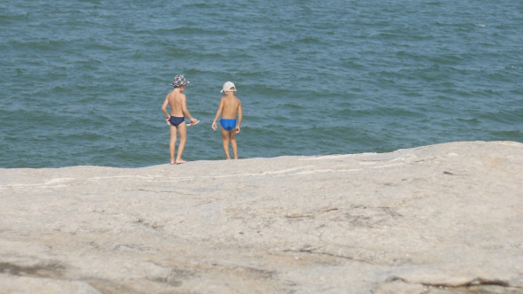 Kids Playing On Rock At Sea