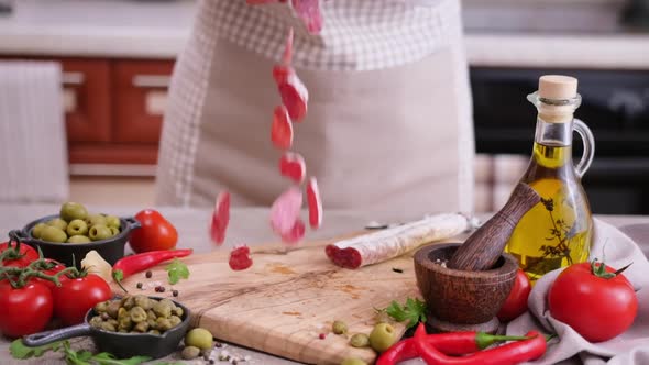 Sliced Fuet Sausage Pieces Falling Onto Wooden Cutting Board at Domestic Kitchen