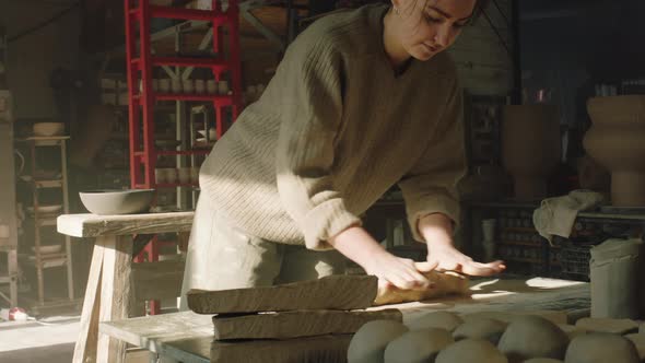 Woman Is Rolling Out Clay Piece On Work Surface
