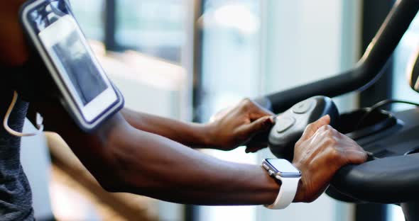 Fit woman with smartphone exercising on exercise bike