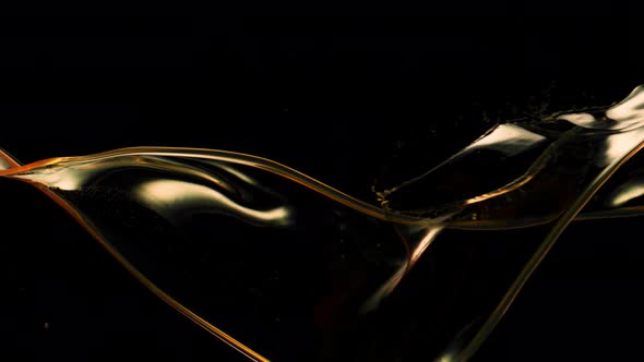 Super Slow Motion Shot of Swirling and Splashing Golden Oil Isolated on Black Background at 1000Fps