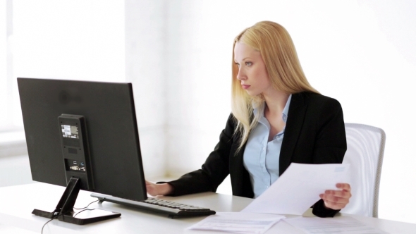 Businesswoman With Computer And Papers At Office