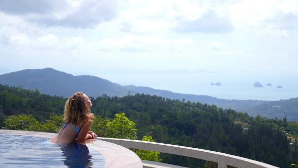 Woman Relaxing In Swimming Pool Enjoying Sea View