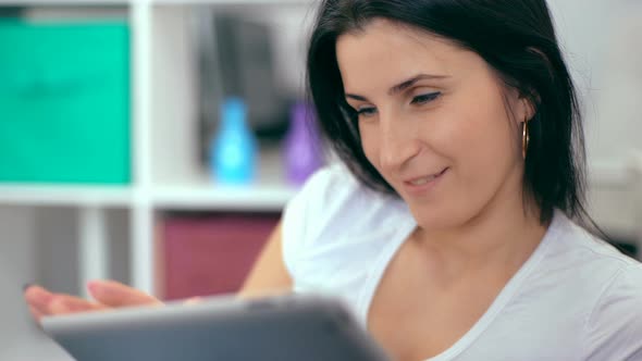 Beautiful Woman Using a Digital Tablet While Sitting on the Couch at Home