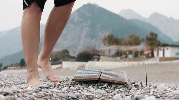 A Woman Kneads Her Legs Before Stepping on a Sadhu Board