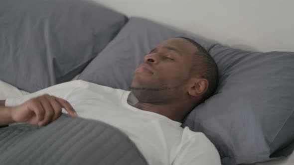 African Man Laying in Bed Unable to Sleep