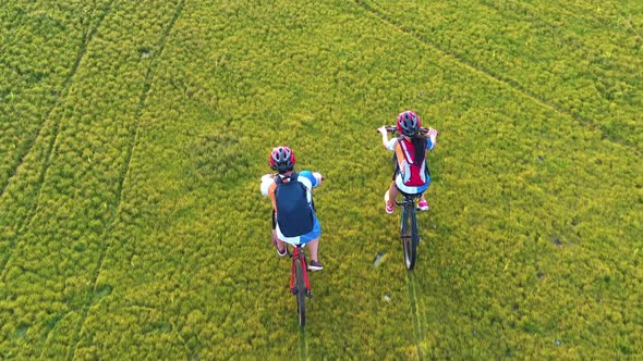 Footage B Roll 4k. Aerial view Drone tracking young People riding a bikes on the meadow