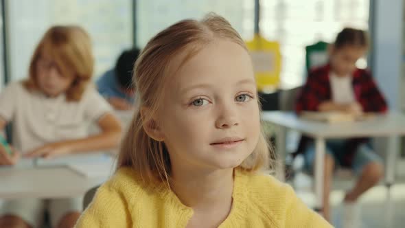 Portrait of the Beautiful Longhaired Blonde Pupil Girl Looking at the Teacher and Attentively