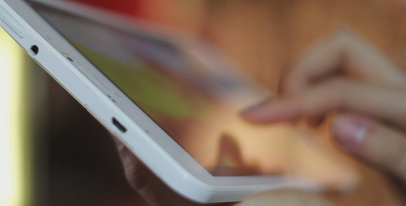 Girl Uses a White Tablet in Cafe