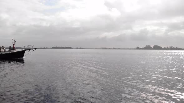 pleasure yacht sailing on a fairway marked by a beacon of light on a cloudy day at a dutch lake. Dro